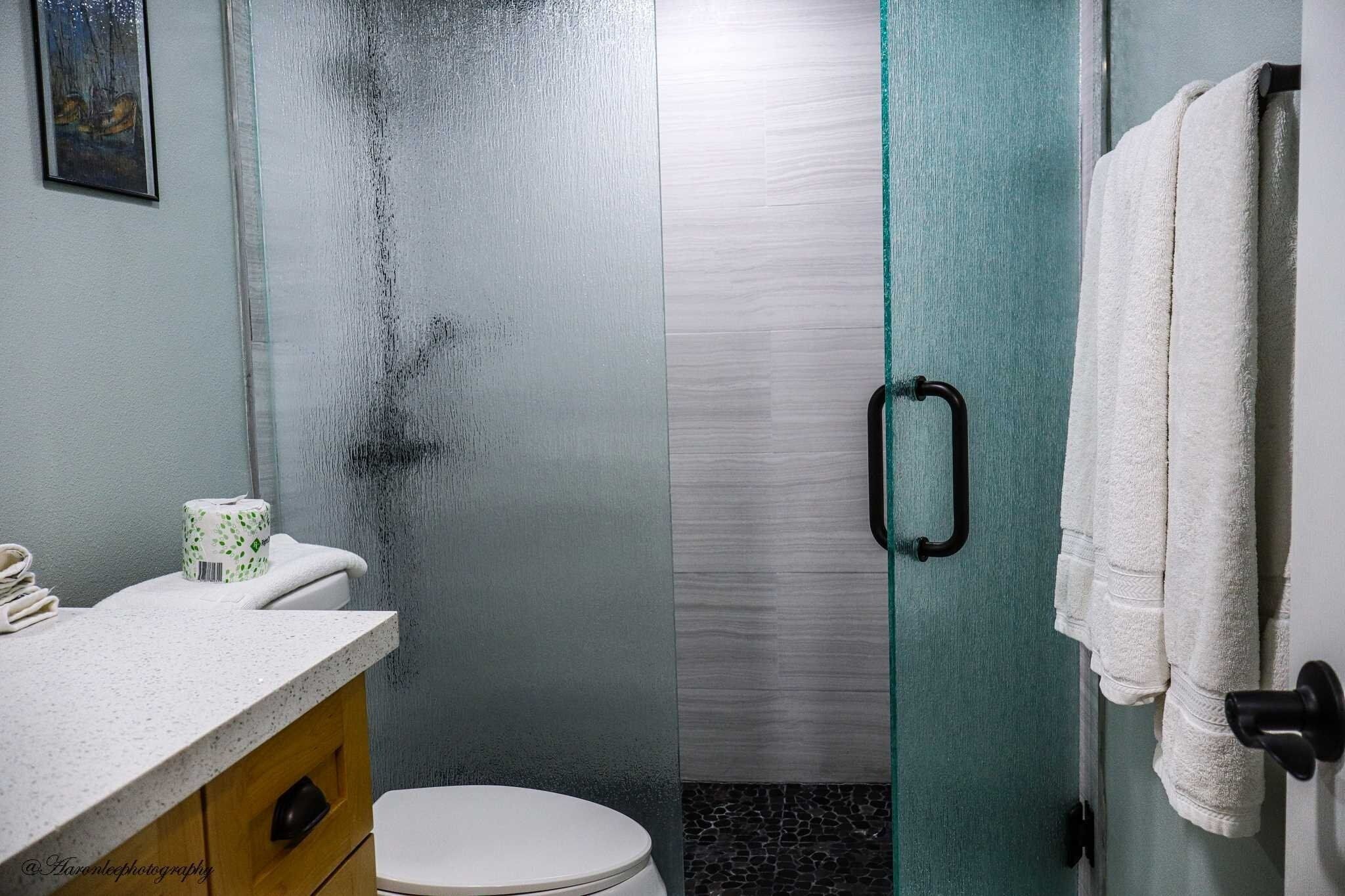 A bathroom with a shower, toilet, and sink.