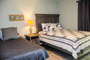 A bedroom with two beds, a bedside table with a lamp, and a wall clock.