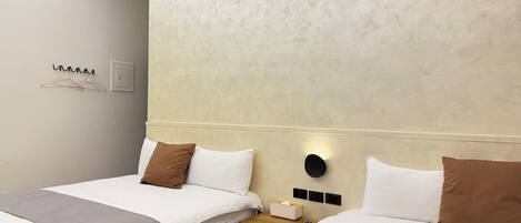 Habitación de hotel con dos camas, una mesita de noche, una lámpara de pared y una lámpara en el techo.
