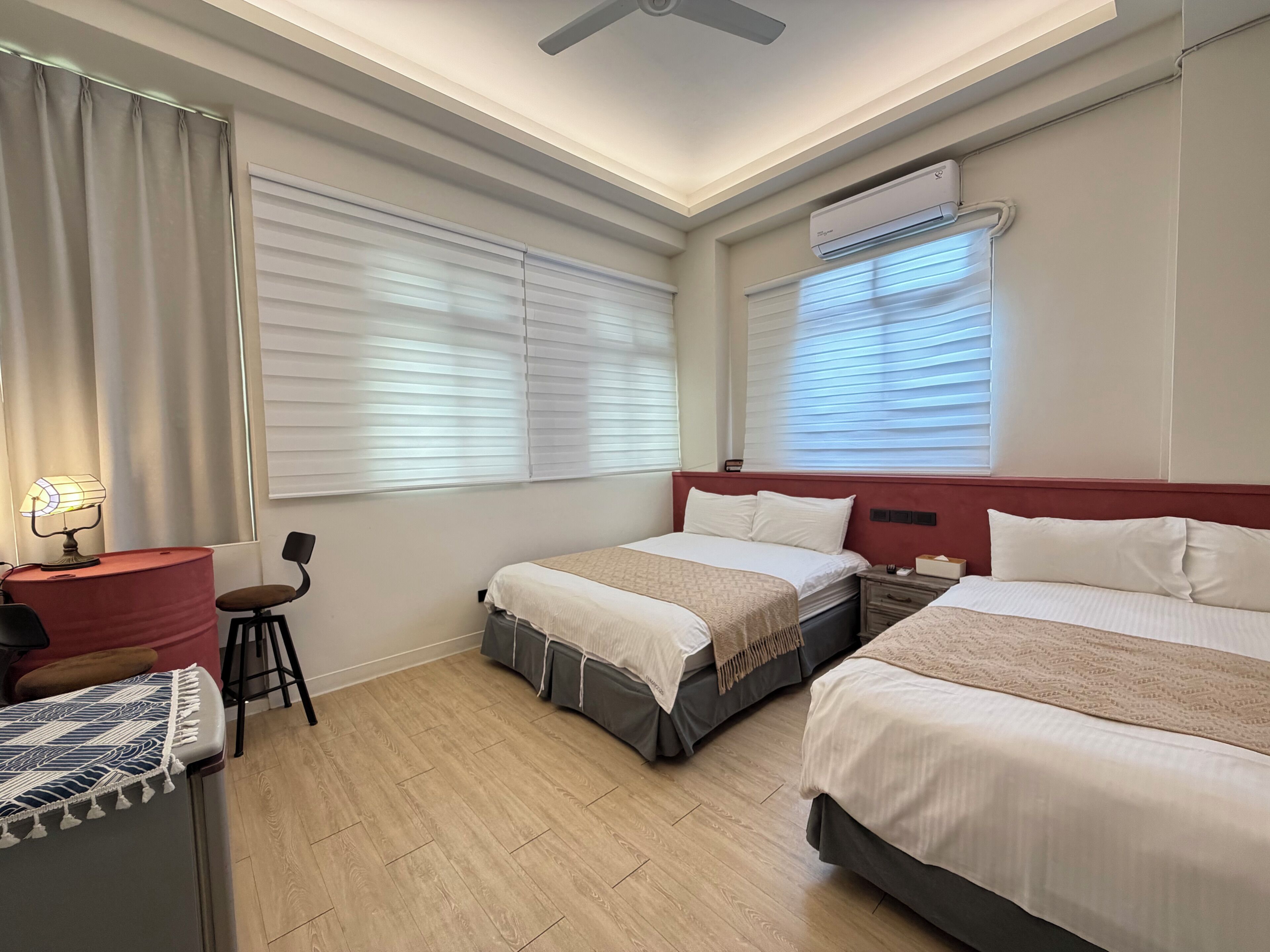 Habitación de hotel con dos camas, un escritorio, una silla y una ventana con persianas.