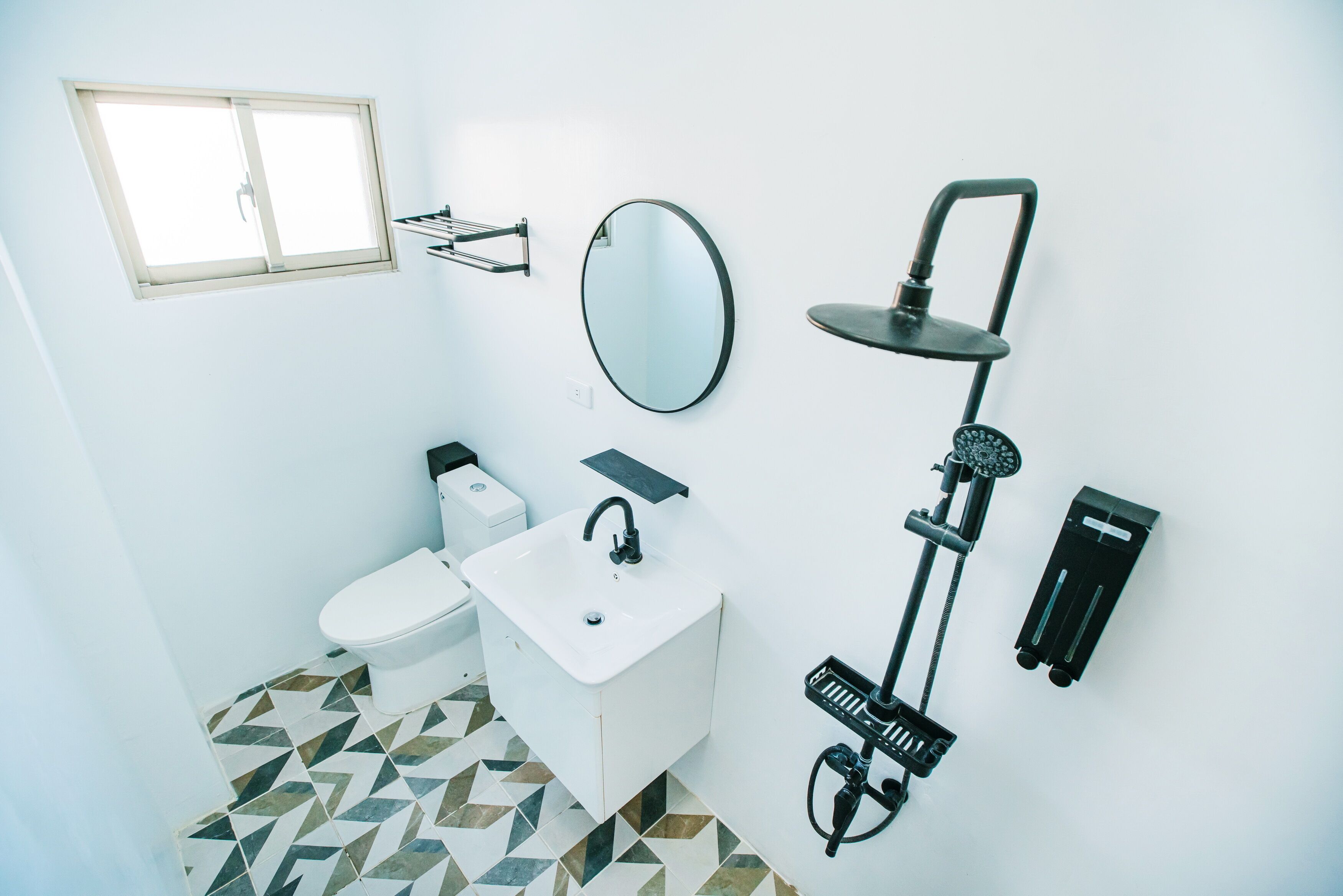 A bathroom with a toilet, sink, mirror, and shower.