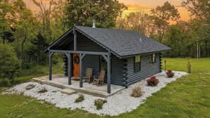 Una baita di legno con un portico, due sedie di legno e una ghirlanda sulla porta.