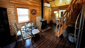 Interno di una baita di legno con zona pranzo, camino e scala.