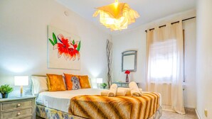 A well-lit bedroom with a bed, nightstands, a lamp, a painting, a mirror, and a window with curtains. - The Beach Holi Apartment by Hello Homes Sitges (Sitges)