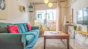 A living room with a teal sofa, a wooden coffee table, and a TV on the wall. - The Beach Holi Apartment by Hello Homes Sitges (Sitges)