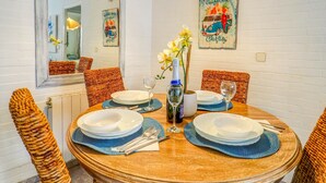 A dining table set with plates, glasses, and a bottle, surrounded by wicker chairs. - The Beach Holi Apartment by Hello Homes Sitges (Sitges)