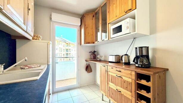 Une cuisine dotée de meubles en bois, d’un four à micro-ondes, d’un grille-pain, d’une machine à café et d’un porte-bouteilles.