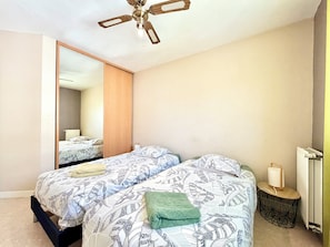 A bedroom with two beds, a ceiling fan, a mirror, and a radiator. - Comfortable T3 at the foot of the Castle of Chambéry! (Chambéry)