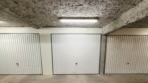 Une rangée de trois locaux de stockage fermés, dotés de portes métalliques et d’un sol en béton.