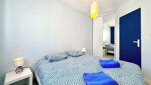 Une chambre à coucher avec un lit, une table de chevet avec une lampe, un miroir et une porte.