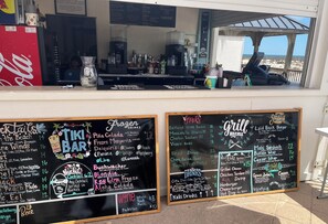 Eine Tiki-Bar mit einer Kreidetafel, die Getränke und Snacks anbietet.