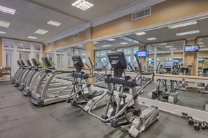 Ein Fitnessstudio mit mehreren Laufbändern, Kraftgeräten und einer Spiegelwand.