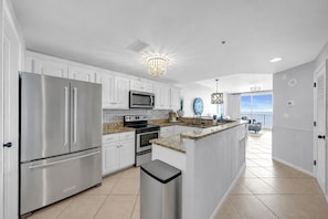 A modern kitchen with stainless steel appliances, a granite countertop, and a view to a balcony.
