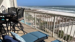 Een balkon met uitzicht op het strand, met ligstoelen en een tafel.