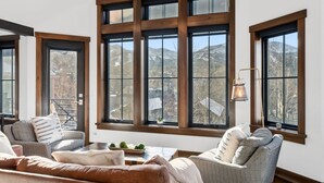 A cozy living room with large windows, a fireplace, and a view of mountains. - Aurum Condo -1 BR w/ Mtn Views, Steps from Main St (Breckenridge)