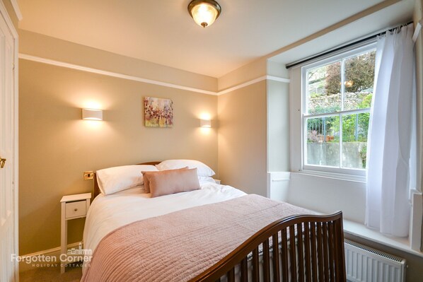 Une chambre à coucher avec un lit, une table de chevet et une fenêtre avec des rideaux.