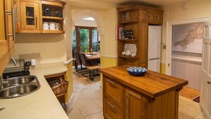 Una cocina con armarios de madera, un fregadero y un comedor con sillas y una mesa.