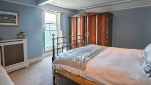 Un dormitorio con cama, armario, ventana con vistas y un cuadro en la pared.