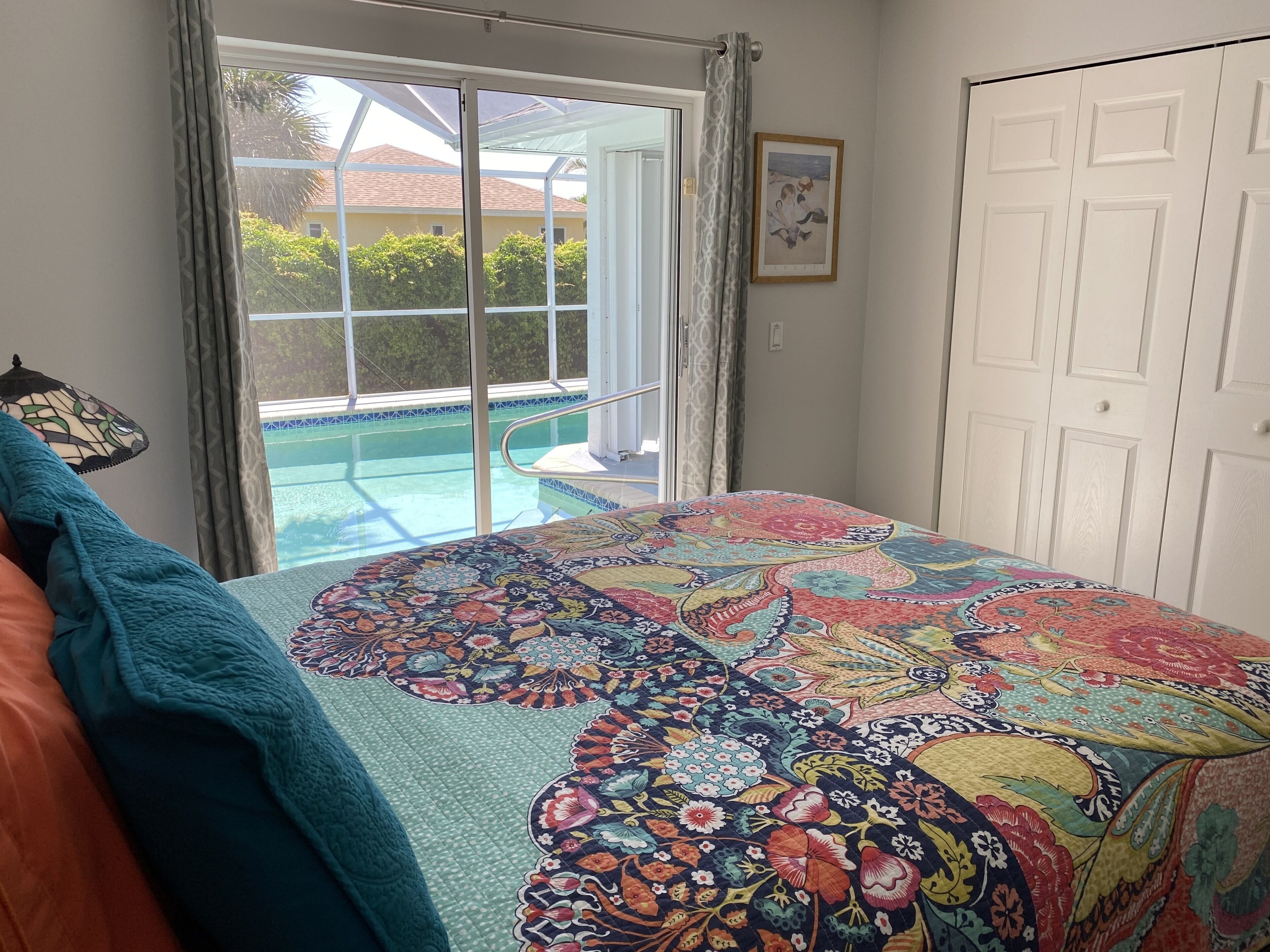 A bedroom with a large bed, a view of a swimming pool, and a door to the outside.