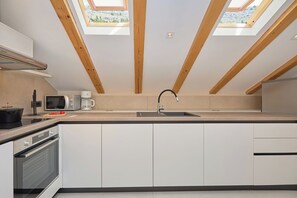 A modern kitchen with skylights, a built-in oven, and a microwave.