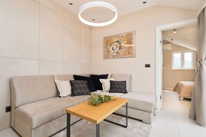 A modern living room with a beige sofa, a wooden coffee table, and a painting on the wall.