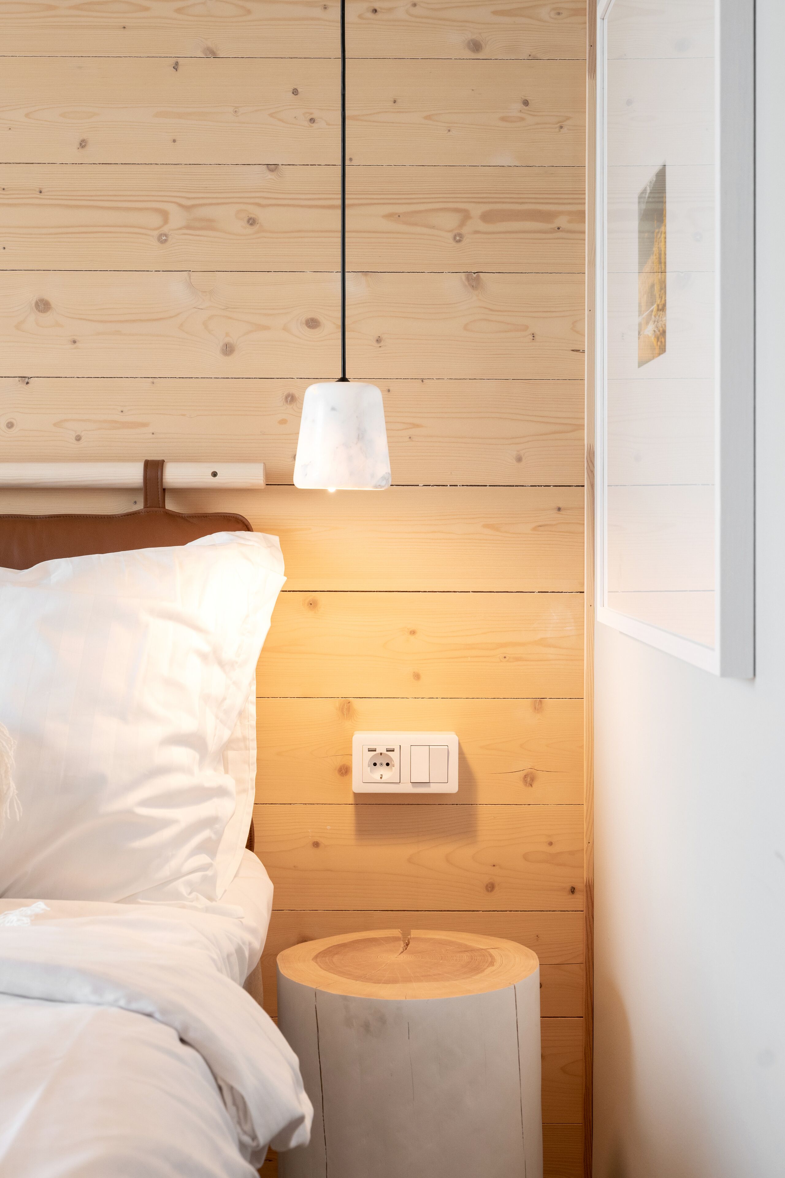 Habitación con paneles de madera, una cama, una mesita de noche y un enchufe.