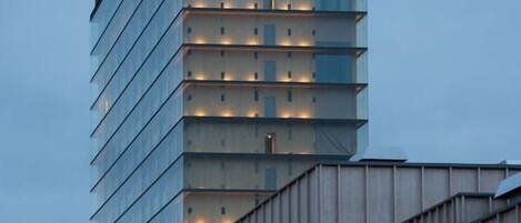 A modern high-rise building with a series of illuminated windows and a flat roof.