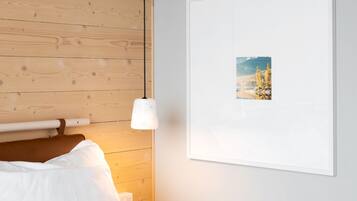 A bedroom with a wooden headboard, a white bedspread, and a framed picture on the wall.
