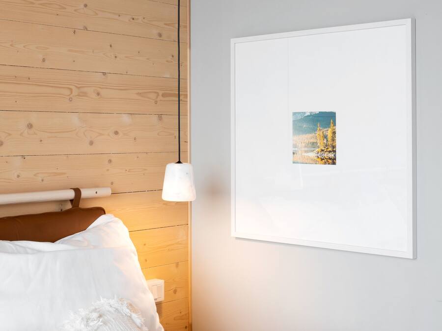 A bedroom with a wooden headboard, a white bedspread, and a framed picture on the wall.
