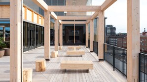 Una terraza moderna al aire libre con bancos de madera y vistas a la ciudad.