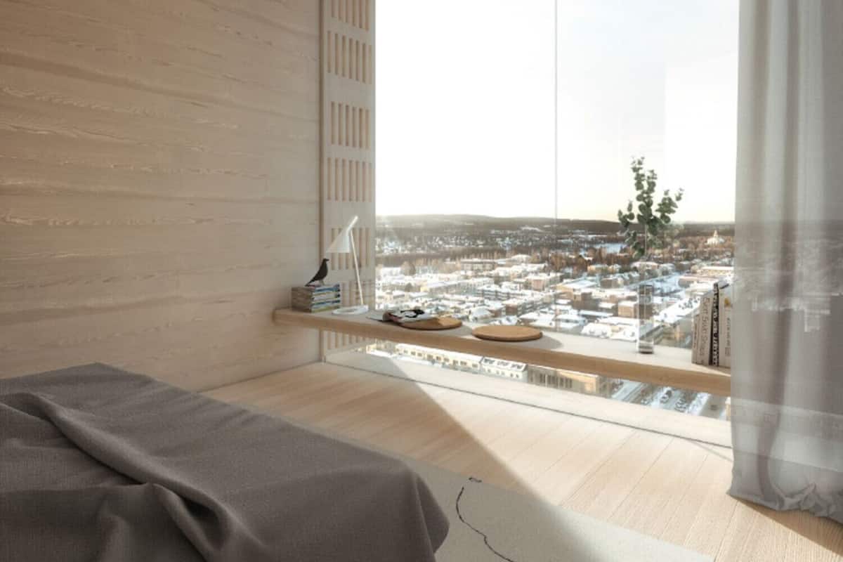 Une chambre moderne avec une grande fenêtre, un lit, une table de chevet avec des livres et une lampe, et une vue sur le paysage urbain.