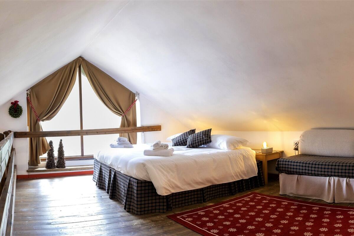 Un dormitorio acogedor con dos camas, un tapete rojo estampado y un cabecero de madera.