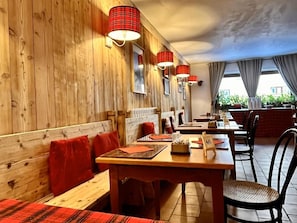 Un restaurant aux murs en bois, aux nappes à carreaux rouges et noirs et aux lampes rouges.