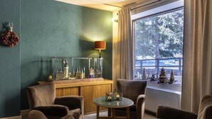 Una habitación acogedora con una pared verde, una barra de madera y un ventanal con vistas a árboles.