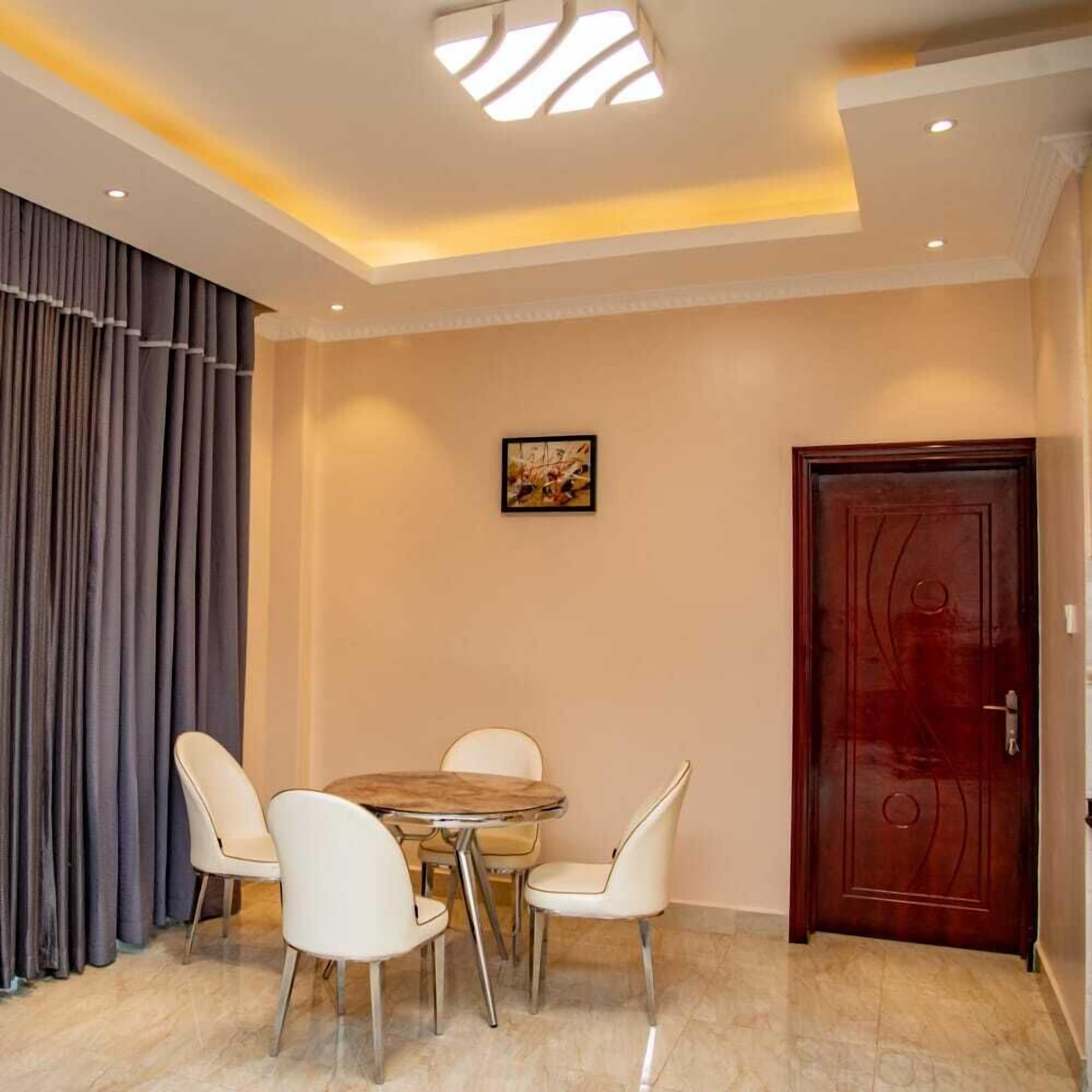 Un coin repas avec une table ronde et quatre chaises, une porte en bois et un tableau accroché au mur.