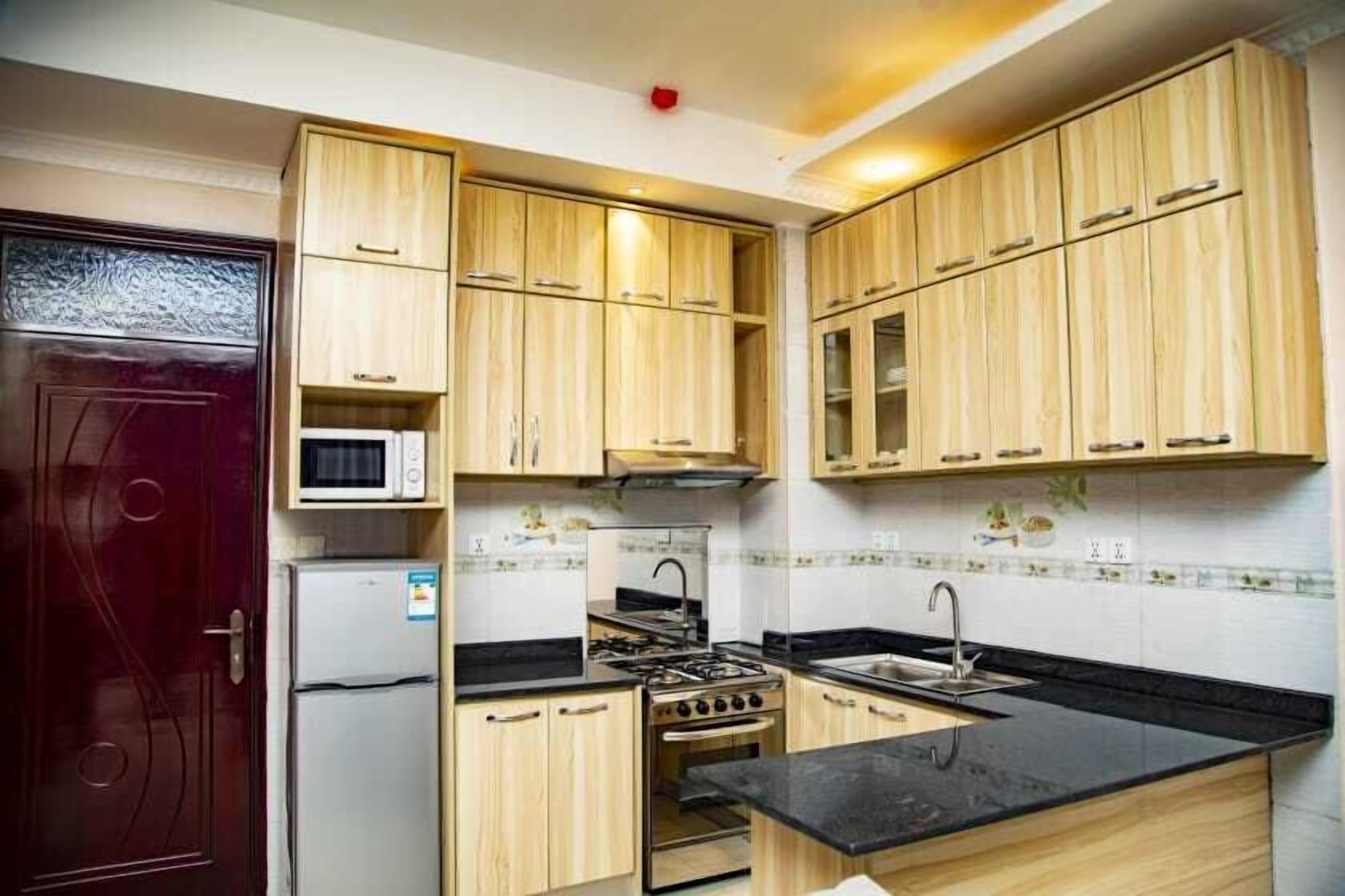 Una cocina compacta con armarios de madera, un microondas, una estufa y un lavamanos.
