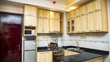 Una cocina compacta con armarios de madera, un microondas, una estufa y un lavamanos.