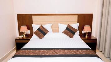 A hotel room with a large bed, two bedside tables with lamps, and a wooden headboard.