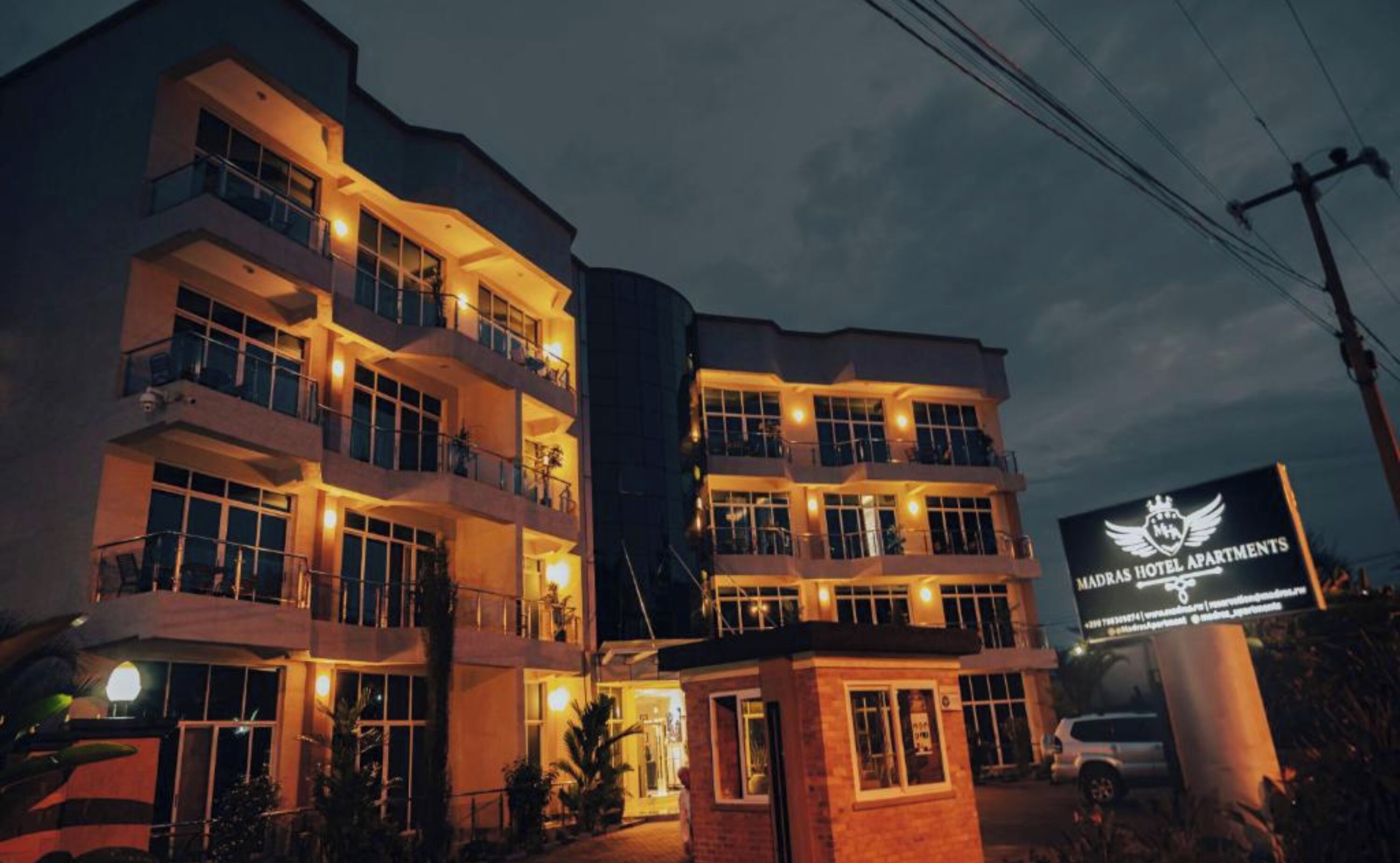 Un hôtel à plusieurs étages, doté de balcons et d’une enseigne indiquant « Madras Hotel Apartments ».
