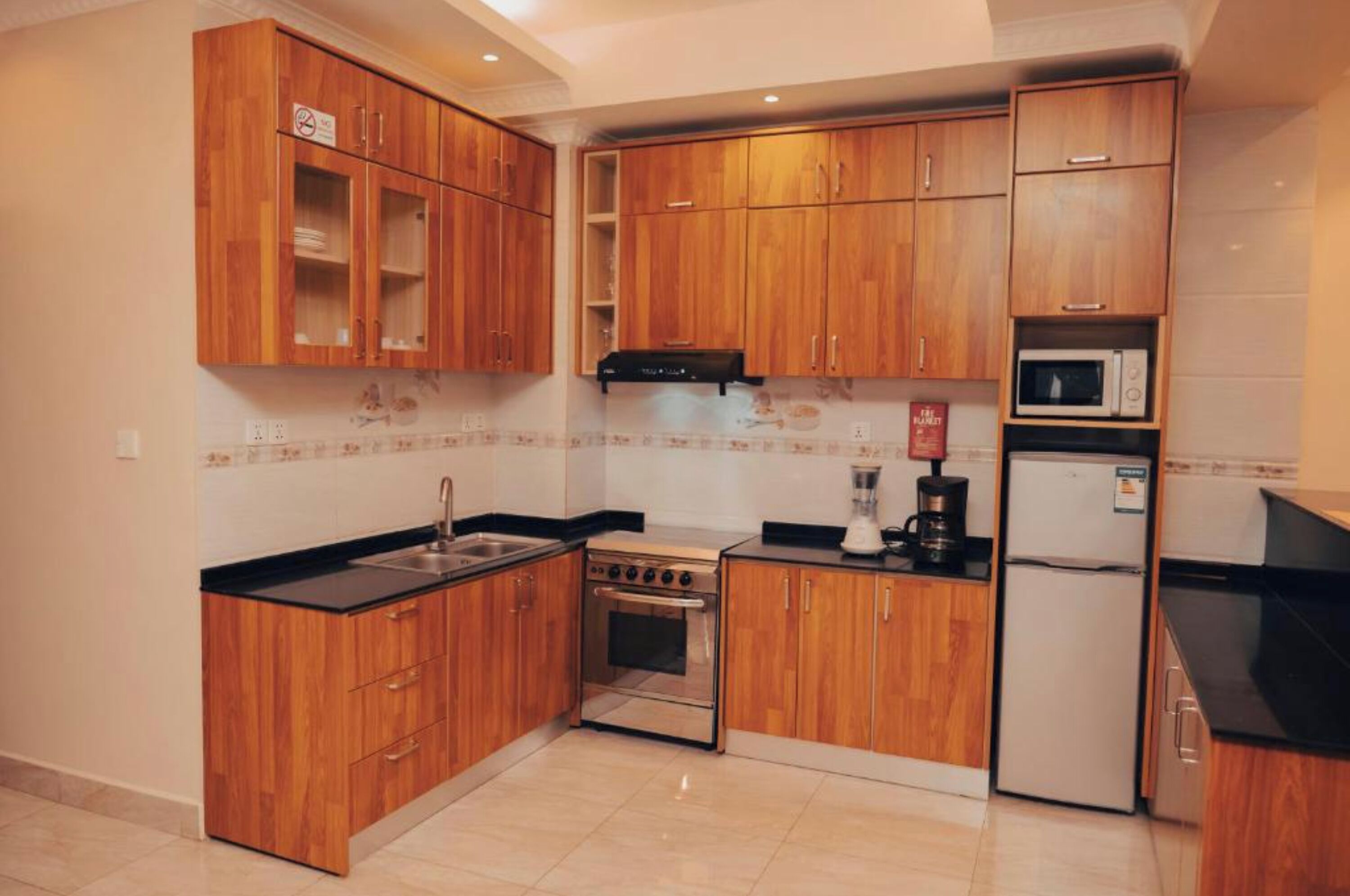 Una cocina compacta con armarios de madera, estufa, microondas y refrigerador.