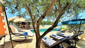 A poolside area with lounge chairs, a tree, and a view of the pool. - Villa Spark **** with pool in Rogoznica / Zečevo (Rogoznoca)