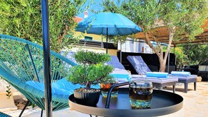 A patio area with a blue chair, a small table with a potted plant, a blue umbrella, and lounge chairs. - Villa Spark **** with pool in Rogoznica / Zečevo (Rogoznoca)