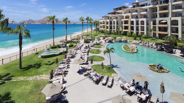 Un resort con piscina, playa y palmeras.