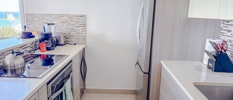 A modern kitchen with a stainless steel refrigerator, a kettle, a toaster, and a coffee maker on the counter.