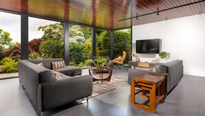 Ein modernes Wohnzimmer mit großem Fernseher, grauen Sofas und einem Holztisch.
