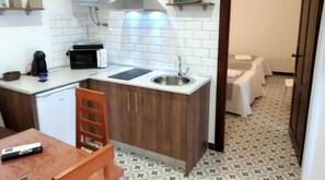 Une cuisine de taille réduite équipée d’un four à micro-ondes, d’un évier et de meubles de rangement en bois.