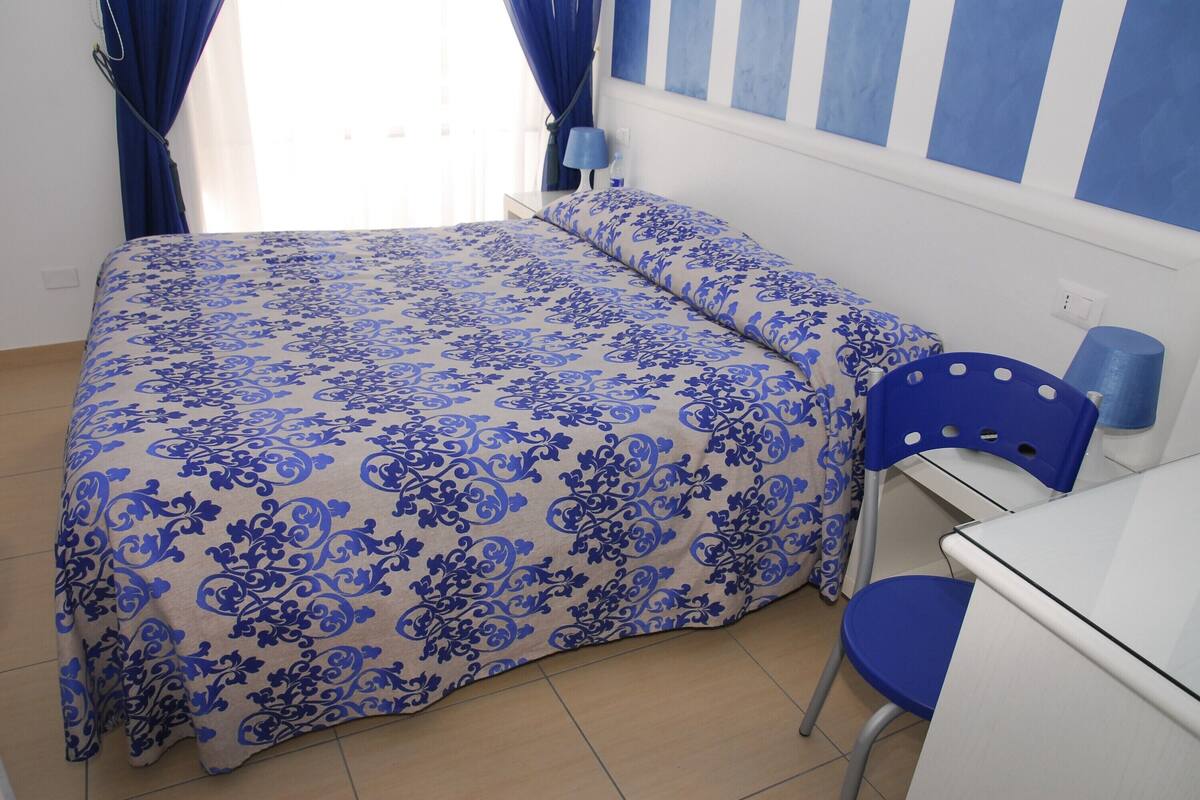A bedroom with a bed, a desk, and a chair.
