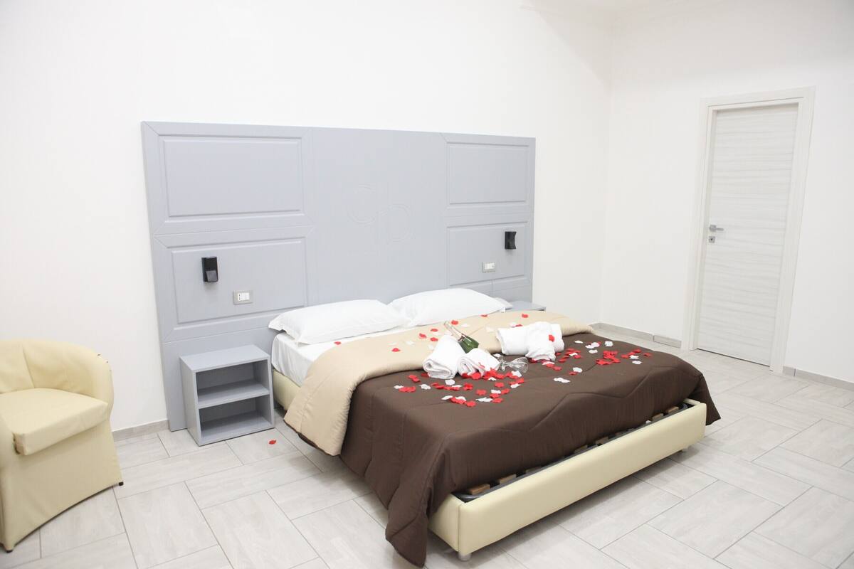 A modern bedroom with a bed, bedside tables, a chair, and a wardrobe.