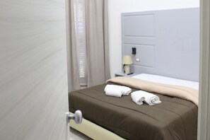 A hotel room with a bed, a nightstand, a lamp, and a door. - Hotel Casablanca (Naples)