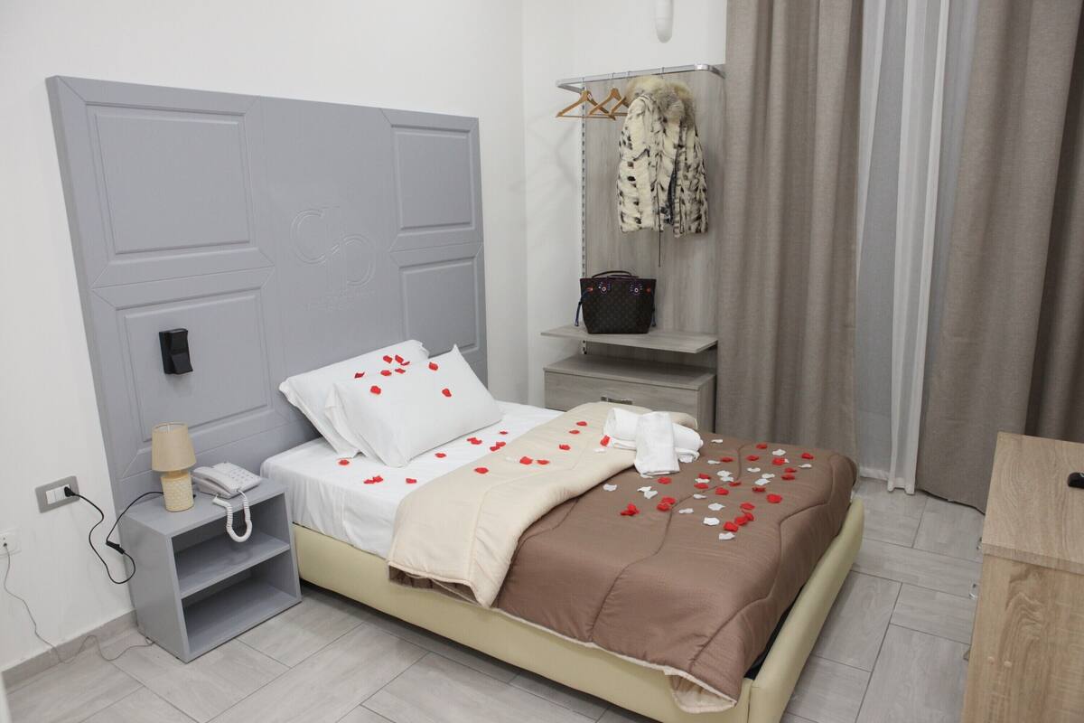 A neatly arranged bedroom with a bed, bedside table, and a wardrobe.